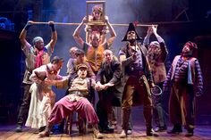 a group of people standing on top of a wooden floor in front of a stage