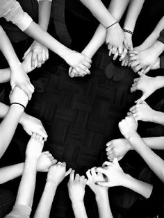 a group of people standing in a circle with their hands on top of each other