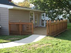 a house with a wooden fence in front of it and grass on the side yard