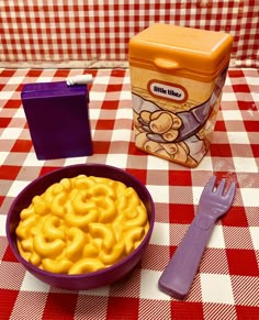 a purple bowl filled with macaroni and cheese next to a container of cereal