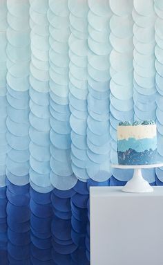 a blue and white cake sitting on top of a table in front of a wall