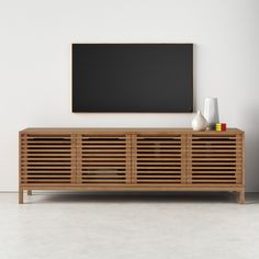 a wooden entertainment center with a blackboard on the wall behind it and vases in front of it