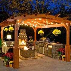 an outdoor kitchen is lit up at night with string lights on the roof and grill