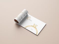 an open wedding ring brochure on top of a pink surface with gold lettering