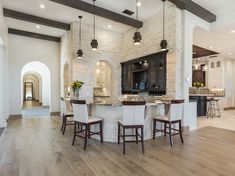 a large kitchen with an island in the middle and bar stools at the end