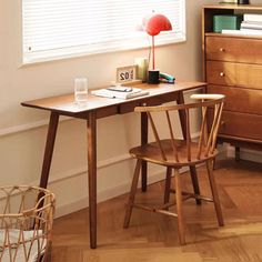 a wooden desk with a lamp on top of it next to a basket filled with books