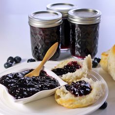 blueberry jam on a plate with biscuits and jelly in the jar next to it