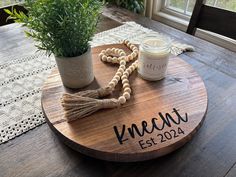 a wooden table with a potted plant on top of it next to a candle