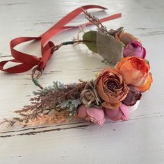 a flower crown made out of dried flowers on a white wooden table with red ribbon