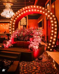 a living room filled with lots of furniture and flowers on the floor next to a chandelier