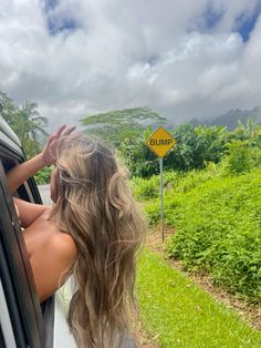 a woman is looking out the window of a car at a road sign that says bump