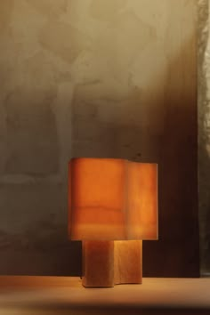 a small wooden block sitting on top of a table next to a wall and lamp