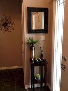 there is a small table with plants on it in front of a mirror and door