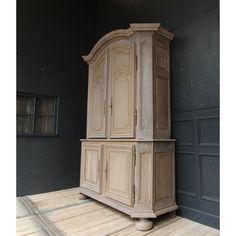 an old wooden cabinet sitting on top of a hard wood floor next to a black wall