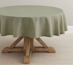 a round table with a green cloth on it's top and two wooden legs