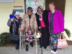 three older women standing next to each other in front of a door with crutches