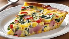 a slice of quiche with ham, cheese and spinach on a white plate