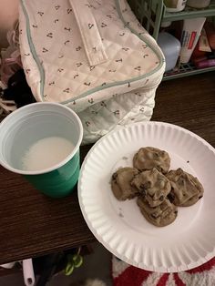 two paper plates with cookies on them next to a cup of milk