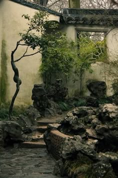 an outdoor area with rocks and trees in the foreground, and a stone path leading up to it