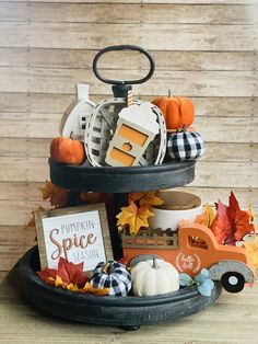 a three tiered tray filled with pumpkins and fall decorations