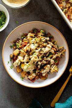 a white bowl filled with food next to bowls of salad and dressing on a table