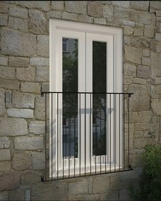 a window with bars on the side of a stone wall next to a planter