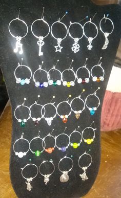 several pairs of earrings are displayed on a black display stand in front of a wooden table