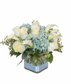 a vase filled with white roses and blue hydrangeas on top of a table