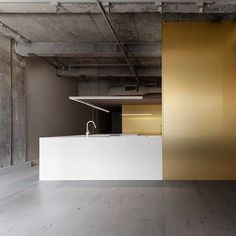 an empty room with white counter tops and gold painted walls, along with a sink in the center