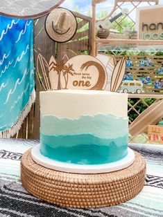 a blue and white cake sitting on top of a wicker tablecloth covered table