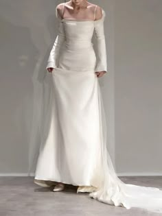 a woman in a white dress is standing on the runway with her hands behind her head