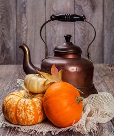 an old tea kettle with pumpkins and gourds on the table stock photo