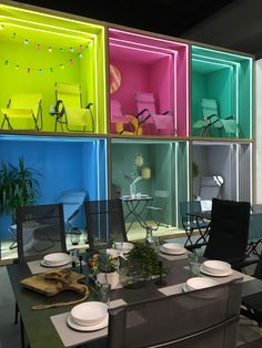 a room filled with lots of different colored glass shelves next to a dining table and chairs