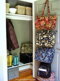 an open closet with several purses hanging on the door and two bags in it