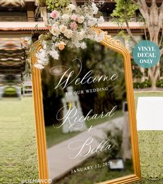 a mirror with flowers on it sitting in front of a sign that says welcome to our wedding