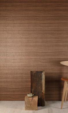 a wooden table sitting next to a lamp on top of a hard wood floor in front of a brown wall