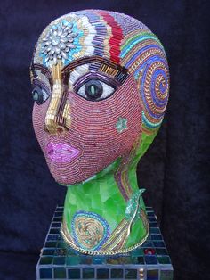 a sculpture made out of glass and beads with a woman's face in the center