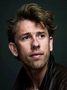 a close up of a person wearing a leather jacket and looking at the camera with a serious look on his face