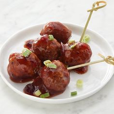 meatballs with ketchup and green onions on a white plate, ready to be eaten