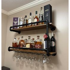 two shelves with wine glasses and liquor bottles on them in front of a wall mounted shelf