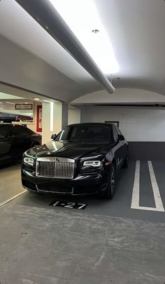 two rolls royces are parked in a parking garage next to each other and one is black