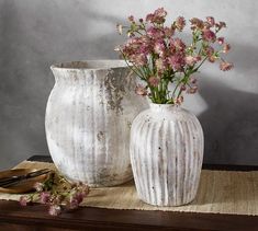 two white vases sitting on top of a table next to each other with flowers in them