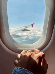 someone is looking out an airplane window at the clouds