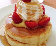 a stack of pancakes topped with whipped cream and strawberries