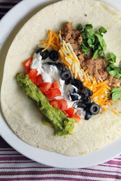 a tortilla filled with meat, cheese and veggies in a white bowl