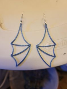 the earrings are made out of blue thread and have an umbrella design on each side