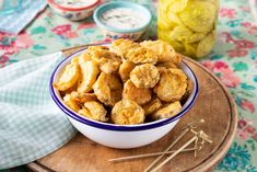 a bowl filled with fried food on top of a wooden plate