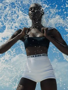 a woman standing in the water with her hands on her hips as she splashes around