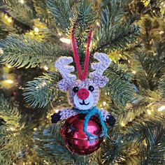 a christmas ornament hanging on a tree with lights in the background and an ornament that looks like a reindeer