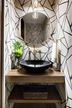 a black bowl sink sitting on top of a wooden counter in front of a mirror